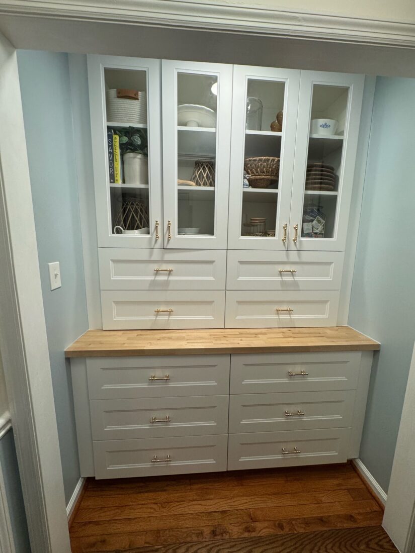 Finished built-in pantry with glass-front uppers and butcher block counter