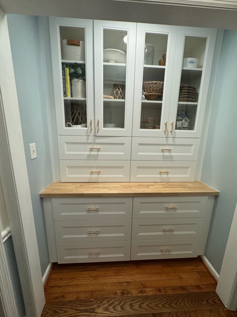 After: white built-in pantry with glass-front upper cabinets, drawers, and a butcher block counter