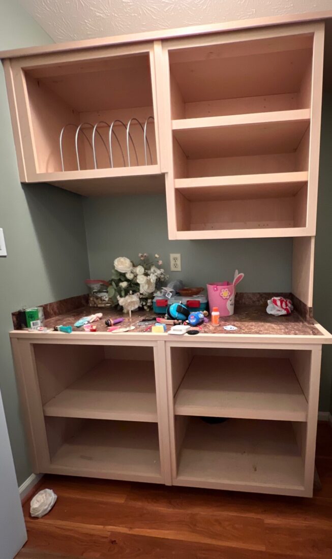 Before: the old laundry closet with unfinished open cabinets and a laminate counter
