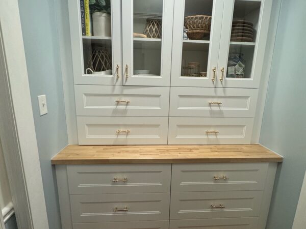 Built-in pantry with glass-front upper cabinets, drawers, and a butcher block counter