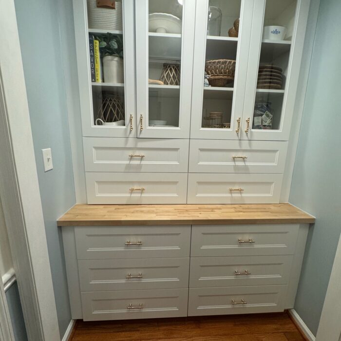 After: white built-in pantry with glass-front upper cabinets, drawers, and a butcher block counter