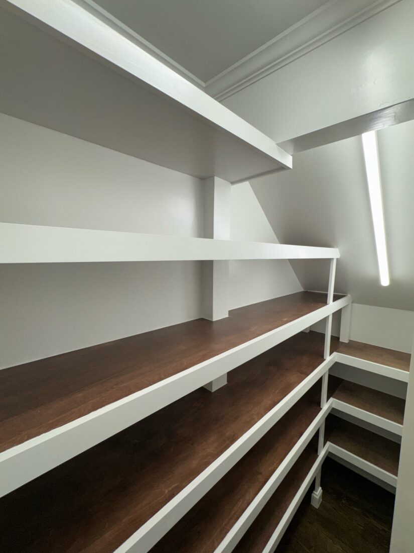Wraparound pantry shelves with white supports and dark stained wood shelf tops