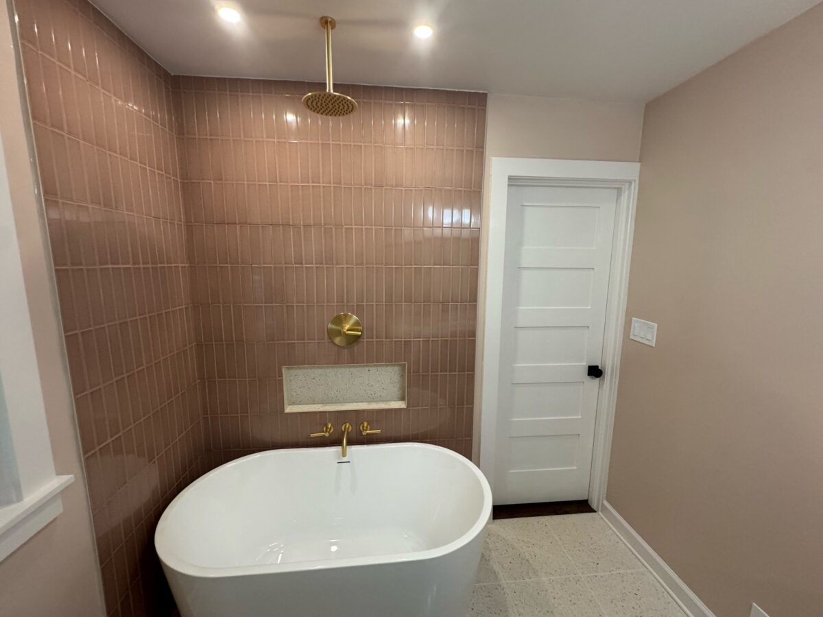 Pink vertical stacked tile shower wall with a built-in niche and freestanding tub